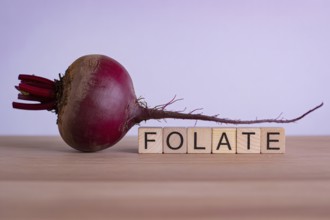Crimson beetroot with wooden blocks spelling Folate. Generative ai, AI generated