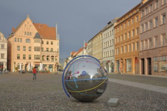 Historic houses with mood lighting on the market square, metal ball with reflection and inscription