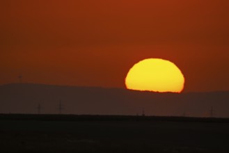 The sun rises behind the Winterstein (left) in the Wetterau, Frankfurt am Main, Hesse, Germany