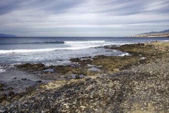 Long rocky coast with gentle waves under a slightly cloudy sky, &enerife, Canary Islands