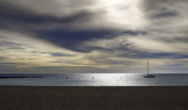 A sailboat anchored in calm waters under a dramatic cloudy sky, Tenerife, Canary Islands