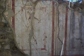 Weathered fresco with red decorative elements on ancient wall, Archaeological site, House of Beluga