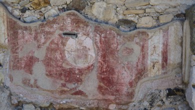 Decorated ancient wall fragment with red elements and traces of weathering, Archaeological Site,