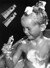 Child washing hair with shampoo, 1930, A child with shampoo in his hair and soap on his body holds