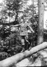 Boy balancing on tree trunk, Boy in suit balancing on a tree trunk in the forest, Historical photo