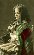 1920 Girl dressed as grandma knitting, girl with knitting needles and glasses in traditional dress