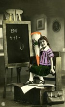 1920 A girl's first day at school, child with a sugar cone in front of a blackboard in a vintage