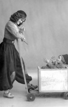 Nanny joking with child in wooden wagon, 1920, Girl pulling a little boy in a wooden toy wagon,