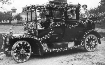 Wedding car with flowers, 1910s, A happy family sits outside in a vintage car decorated with