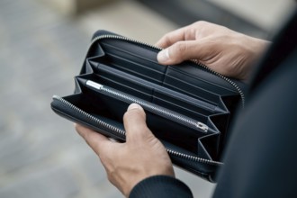 Hands holding empty black wallet. Concpet for financial struggle and economic hardship. Generative