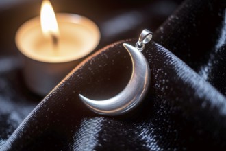 Silver crescent moon pendant glowing in candlelight on black velvet, symbol of witchcraft and lunar