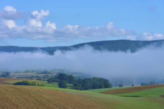 Fog moves through hilly landscape with blue sky, Mönchberg, Miltenberg, Spessart, Bavaria, Germany