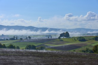 Picturesque fields with fog and blue sky in a hilly landscape, Schmachtenberg, Miltenberg,