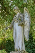 Stone angel in a green garden, surrounded by trees, atmosphere is quiet and peaceful, cemetery,