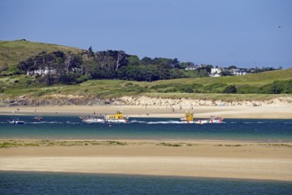 Two boats on the sea with green hills and a clear sky in the background, Padstow, Cornwall,