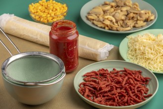 Ingredients for preparing a pizza arranged on a green table