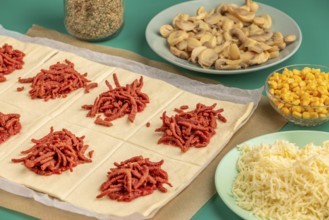 Sliced dough squares with tomato paste and bacon alongside other ingredients for pizza, balls