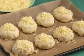 Raw pizza, balls with grated cheese on baking paper, ready for the oven
