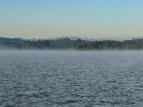 Light fog over Lake Starnberg with a view of the Alps, Bavaria, Germany