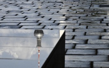 The top of the television tower is reflected on a stone pedestal on the north side of the Reichstag