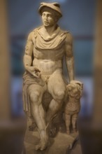 Ancient marble sculpture of a seated man next to a ram, Hermes, seated, on display in the museum,