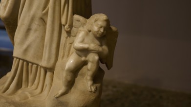 Marble sculpture of a small angel as part of a larger statue, carved in classical style,