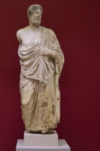 Marble statue of a bearded man in classical pose, surrounded by cloths, Archaeological Museum, Kos