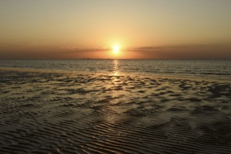 Sunset over the Wadden Sea on the German North Sea coast, typical ripple mudflats at low tide,