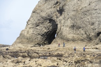 Large rock with a hole and people in the foreground, Hole in The Wall, Rialto Beach, Olympic