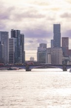 Modern cityscape with skyscrapers and a bridge across a river at sunset, London, United Kingdom,