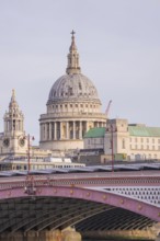 Bridge in front of a large cathedral with distinctive dome and towers, London, United Kingdom,