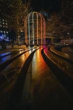 Night scene with colorful illuminated pavilion and twinkling lights in an urban setting, London,