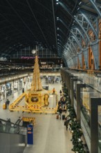 Christmassy decorated station hall with large tree sculpture and lots of people, London, United