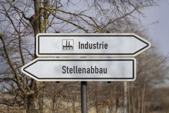 (photo montage) Directional arrows with the inscription INDUSTRY and JOB CUTS