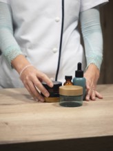 Professional hand arranging various beauty product jars and bottles on a wooden counter