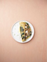 Savory omelet with spinach, crumbled sausage, and lemon wedge on a plate for breakfast