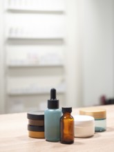 Skincare bottles and jars standing on wooden table with minimalist background