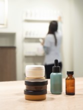 Skincare jars and serum bottles on a wooden table with an aesthetician arranging products in a