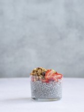 Chia seed pudding layered with fresh strawberries and crunchy granola in a glass