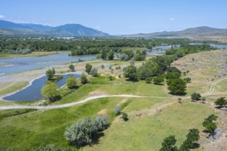 Wide landscape with river, green fields and hills under a blue sky, view from the cave town of