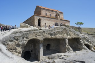 Historic church on a rock with caves and tourists on a clear day, 10th century princely church,