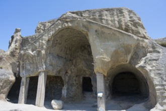 Ancient cave architecture with stone entrances and a clear sky, cave opening with gable fragment,