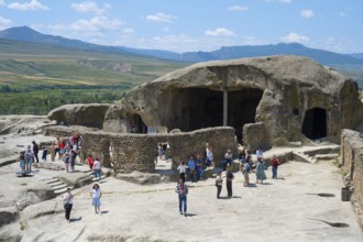 Tourists visit old caves and rock formations on a sunny day, Tamaris Darbasi, Tamara's Hall,