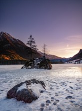 Rock island in frozen Hintersee, footprints on ice, evening light, Berchtesgaden National Park,