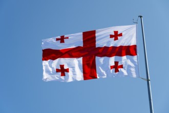 White flag with red crosses flying against a blue sky, flag of Georgia