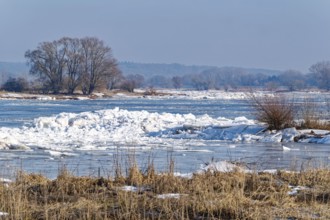 Ice skating on the Elbe and remnants of snow in the foothills of the Elbe on a clear winter day.