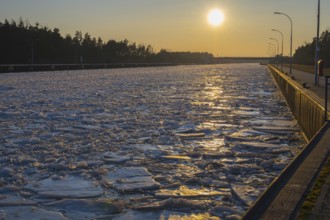 Frozen channel at sunset with reflecting light and wooded banks, ice floes, Elbe-Havel Canal,