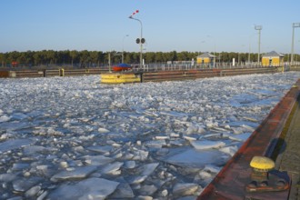 Icy water area at a lock with yellow buoys under clear blue sky, ice floes, Hohenwarthe lock,