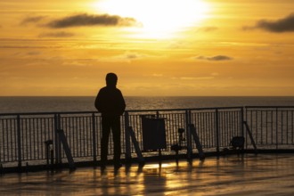 Traveler standing at the railing and looking at the sea at sunset, Finland ferry Helsinki to