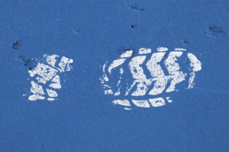 White paint imprint of a shoe sole on a blue painted surface